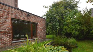 A brick building with a large window and a small pond with lily pads. - West Flanders Vacation Home (Comines-Warneton)