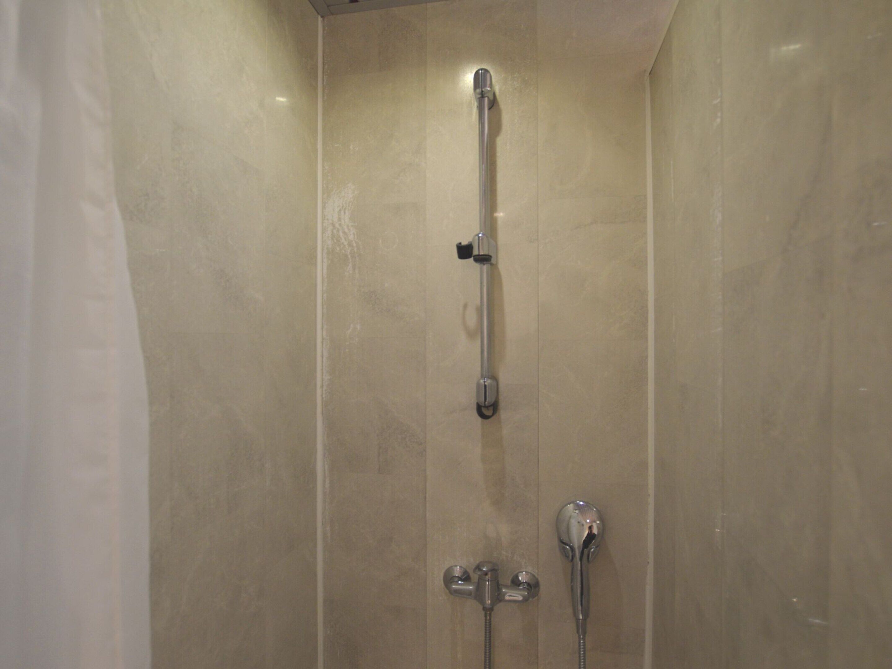 Eine Dusche mit Handbrause und Armaturen an der Wand.