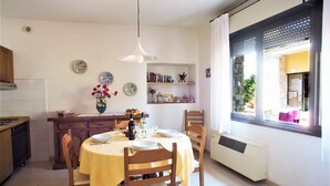A dining area with a round table, chairs, a vase with flowers, and a bookshelf. - Cottage in Chianti With Pool & Vineyard Views (Barberino Tavarnelle)
