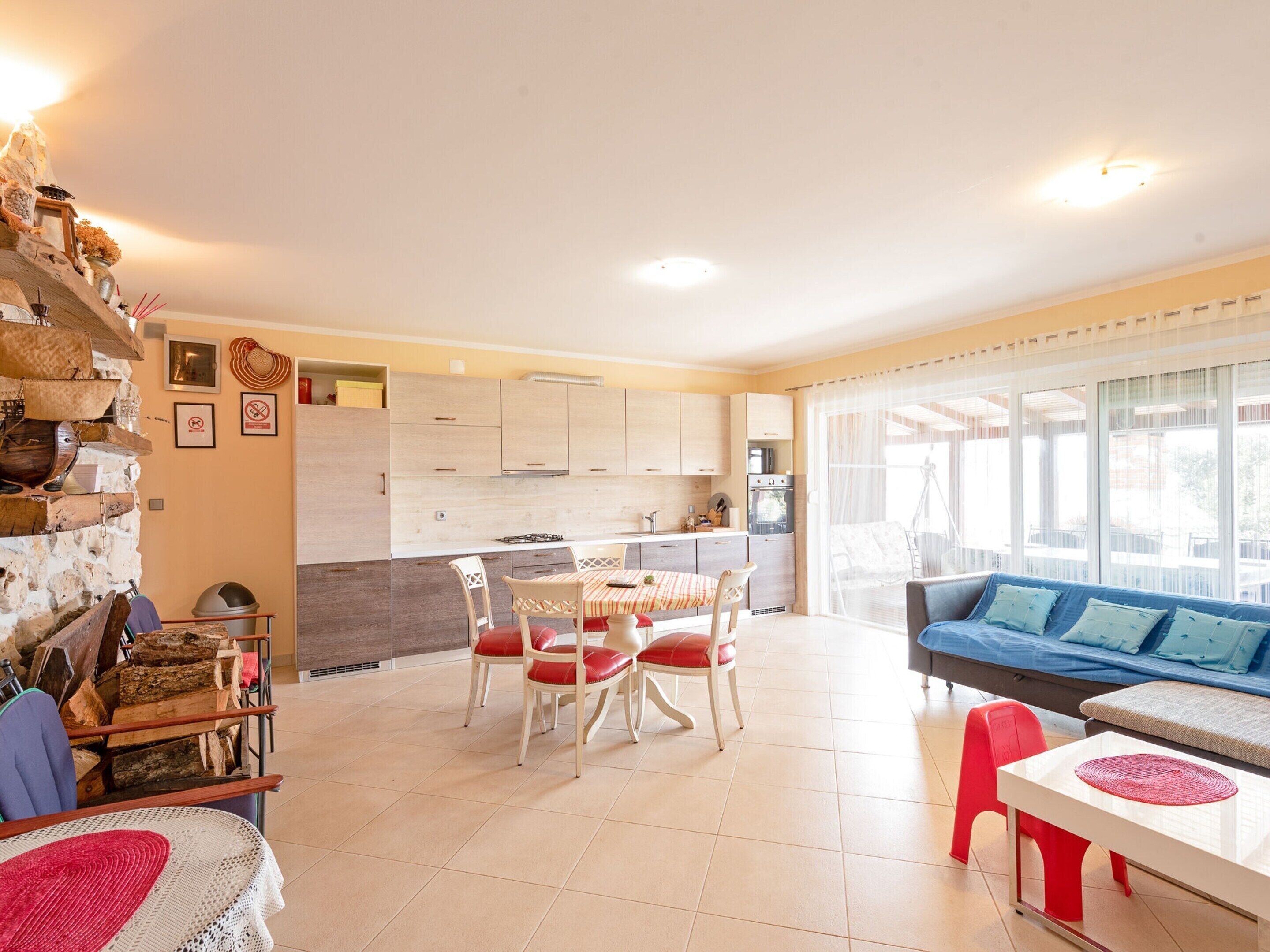 Une cuisine moderne avec des meubles blancs, un coin repas avec une table et des chaises, et un salon avec un canapé et un téléviseur.