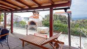 An outdoor patio with a stone oven, wooden furniture, and a view of a coastal area. - Modern Holiday Home in Mandre With Barbeque (Zmijavci)