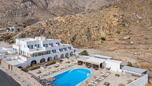 Een resort met een zwembad, terras en uitzicht op rotsachtige bergen.