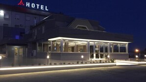 Un hotel moderno con fachada de vidrio y una entrada bien iluminada.