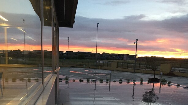 Pavimento mojado que refleja luces y el atardecer.