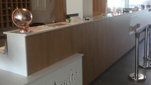 Un mostrador de recepción con encimera de madera y un adorno de globo metálico. Hay un reloj en la pared y una vitrina de vidrio.