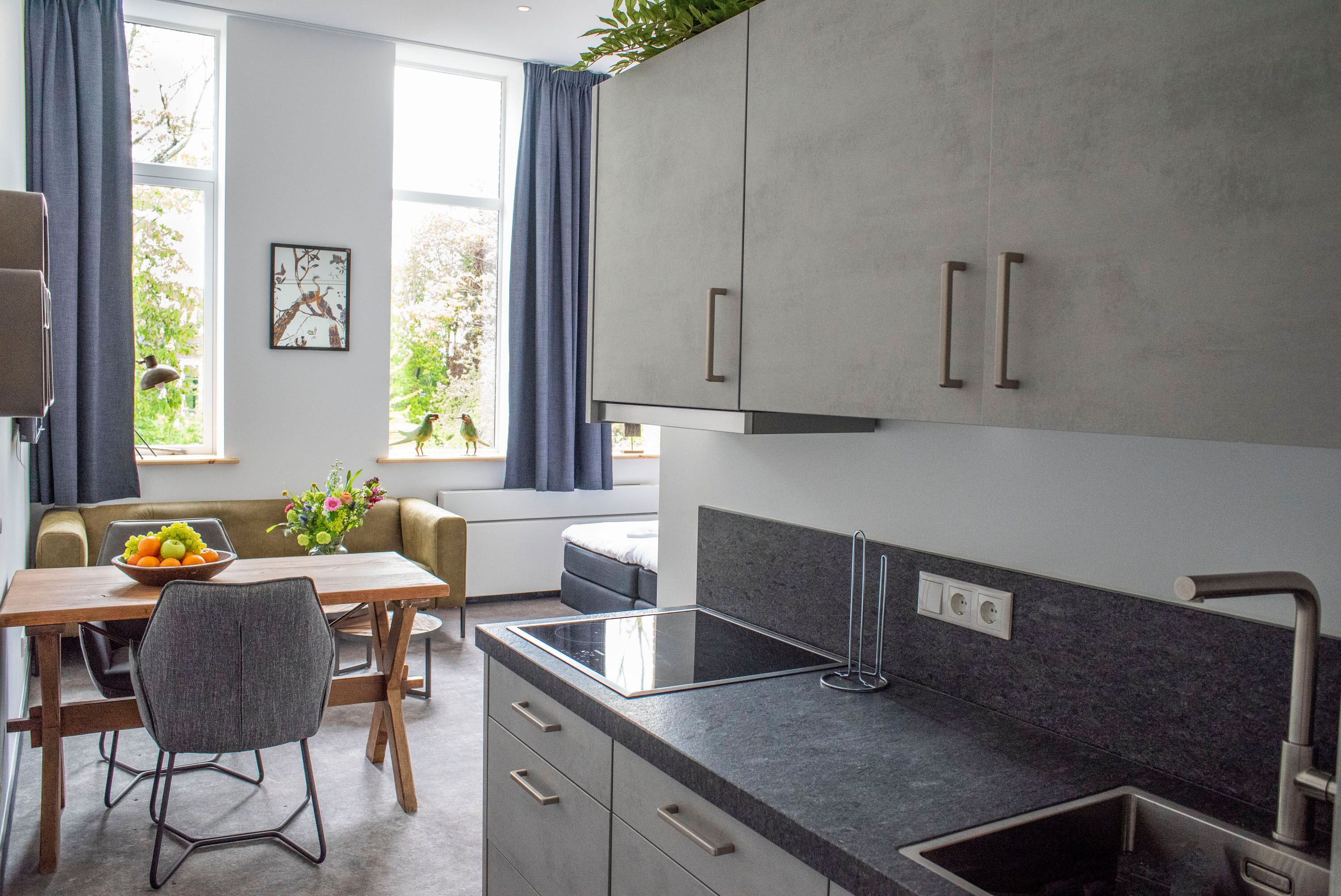 A modern kitchen with a built-in stove, a sink, and a dining area with a table and chairs.