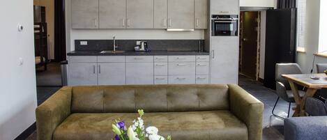 Een moderne keuken met grijze kastjes, een zwart aanrecht en een ingebouwde oven.
