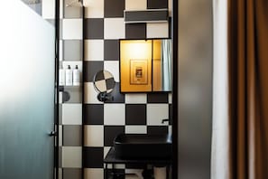 A bathroom with a black sink, a mirror, and a framed picture on the wall. - L’Hotel Journal (Tel Aviv)