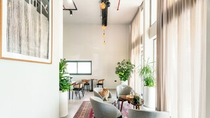 Um interior moderno com área de jantar, cadeiras, tapete e plantas em vasos.