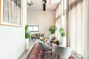 Un interior moderno con comedor, sillas, alfombra y plantas en macetas.