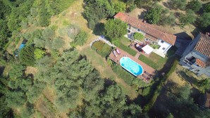 Vista aerea di una proprietà con piscina, patio e una casa con tetto in tegole.