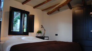 Una camera da letto con un letto, una finestra vista, un armadio scuro e un tavolino con una pianta.