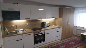 A modern kitchen with white cabinets, a built-in oven, a coffee maker, and a sink. - Stadthaus Franz Josef (Hallein)