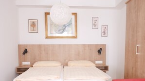 A double bed with a wooden headboard, two bedside tables, a red sofa, and a hanging light fixture. - Stadthaus Franz Josef (Hallein)