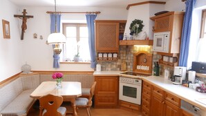 A cozy kitchen with wooden cabinets, a built-in oven, and a dining area with a bench and table. - Stadthaus Franz Josef (Hallein)