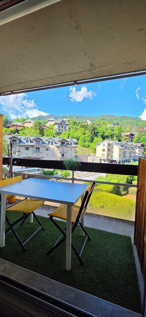 Een balkon met een tafel en stoelen, met uitzicht op een woonwijk met huizen en groen.