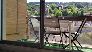 A balcony with a view of a hillside and buildings. There is a table and two chairs. - Elegant and modern, at the foot of Mt-Blanc (Saint-Gervais-les-Bains)