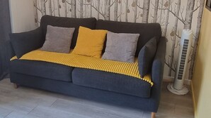 A modern living room with a dark grey sofa, a yellow throw blanket, and a wall with a tree pattern. - Elegant and modern, at the foot of Mt-Blanc (Saint-Gervais-les-Bains)