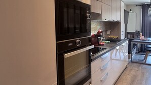 A modern kitchen with a built-in oven, microwave, and a coffee machine on the counter. - Elegant and modern, at the foot of Mt-Blanc (Saint-Gervais-les-Bains)