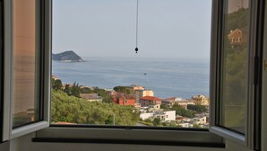 A view from a window overlooking a coastal town with buildings and a small island in the distance. - Maiso house nestled between the sea and olive trees (Lavagna)
