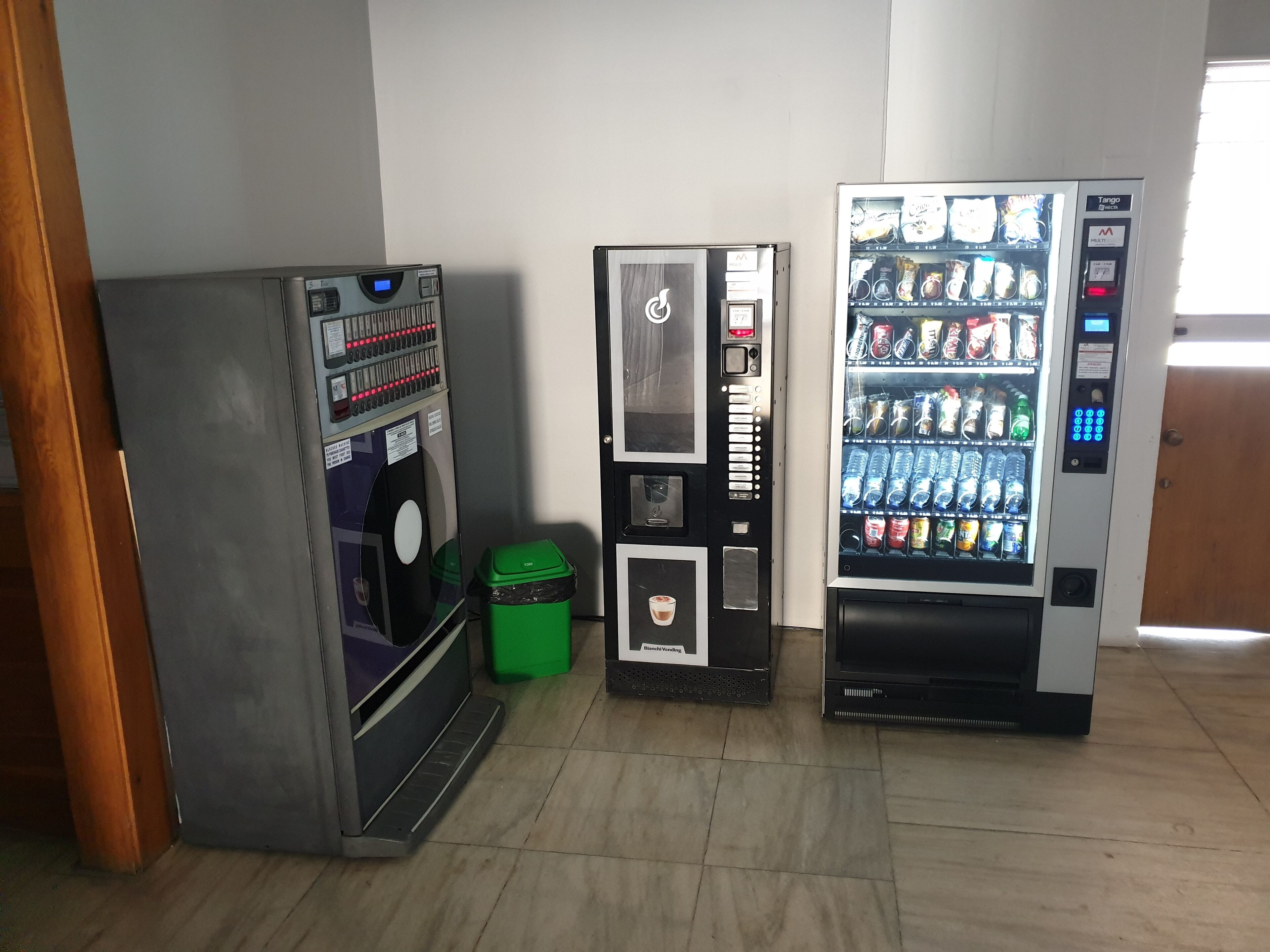 Tres máquinas expendedoras en una habitación con suelo de baldosas.