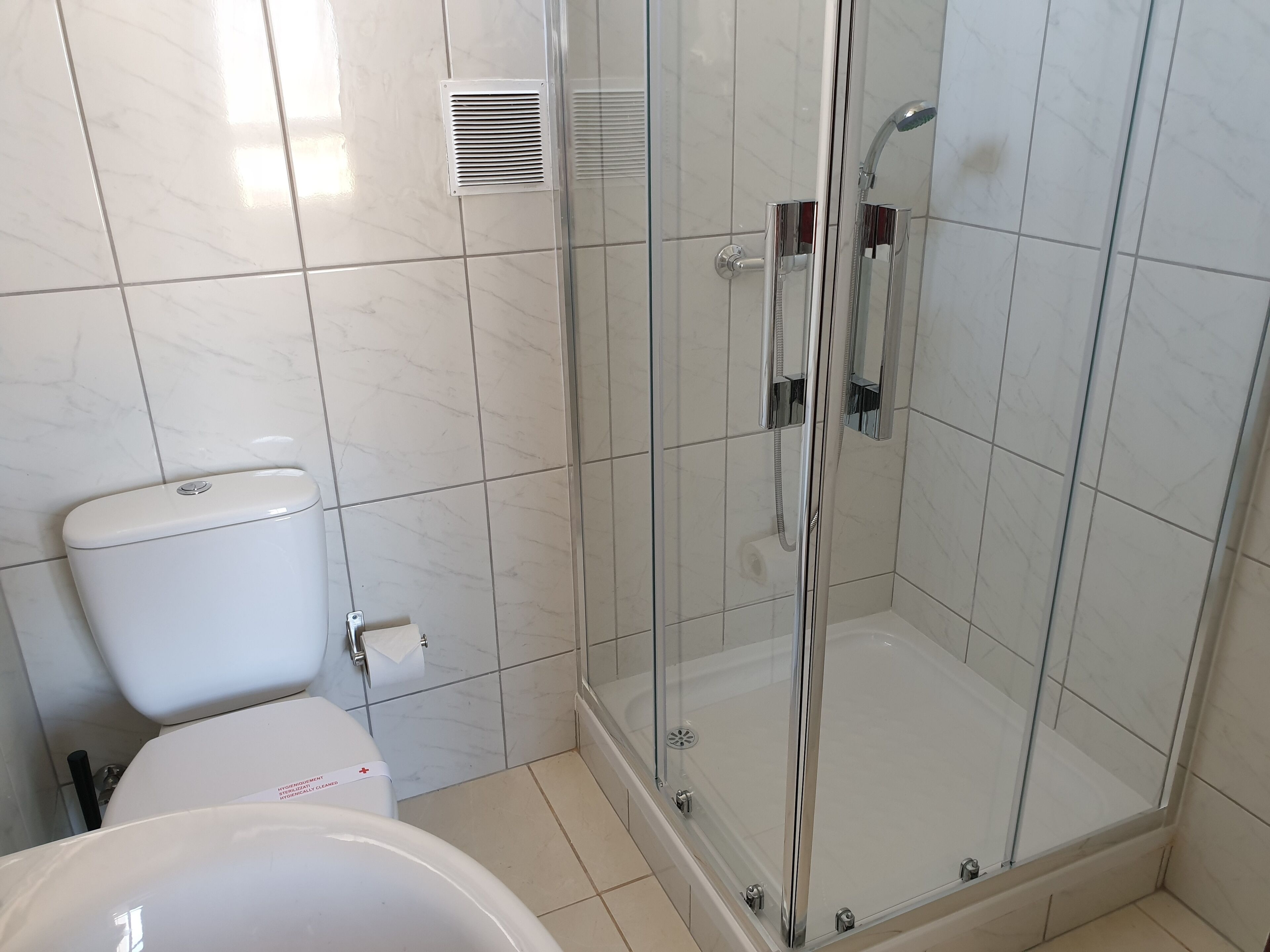 A bathroom with a toilet, a glass-enclosed shower, and a bathtub.