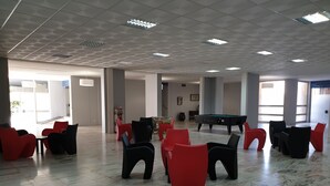 A spacious indoor area with a pool table, red and black chairs, and a marble floor. - Tarik  by Atlantichotels (Portimão)