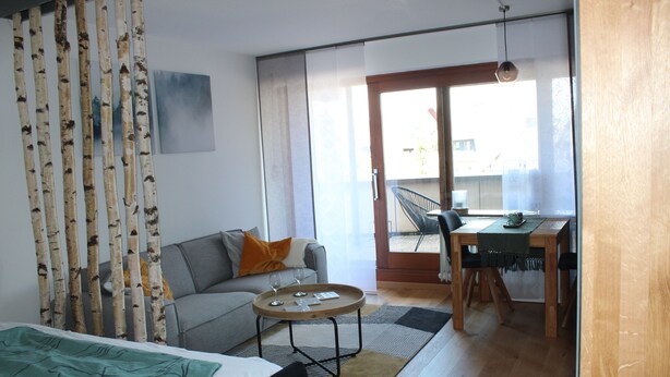 Una sala de estar moderna con sofá, mesa de comedor y una mesita de centro.