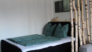 Un dormitorio moderno con cama, una mesita y un adorno en la pared.