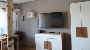 Una sala de estar moderna con un televisor de pantalla plana, muebles de madera y decoración en la pared.