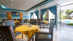 Un restaurante con mesas y sillas redondas, vista a la piscina y un diseño interior moderno.