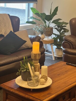 A cozy living room with a brown leather sofa, a wooden coffee table, and a potted plant. - Skibo Cottage (Skibo)