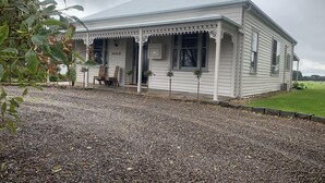 A small, single-story building with a porch and a gravel driveway. - Skibo Cottage (Skibo)