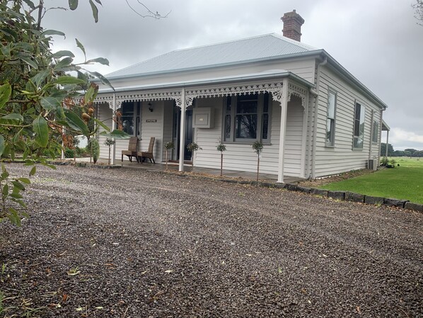 A small, single-story building with a porch and a gravel driveway. - Skibo Cottage (Skibo)