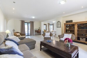Una sala de estar con sofá, sillones, una mesa de centro y una estantería.