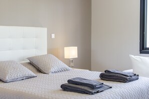 Una cama bien hecha con almohadas, una lámpara y toallas dobladas.