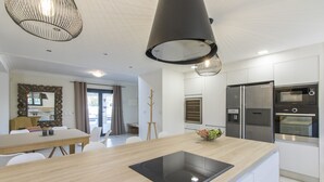 Ett modernt kök med en inbyggd spis, vitvaror i rostfritt stål och en matplats med bord och stolar.