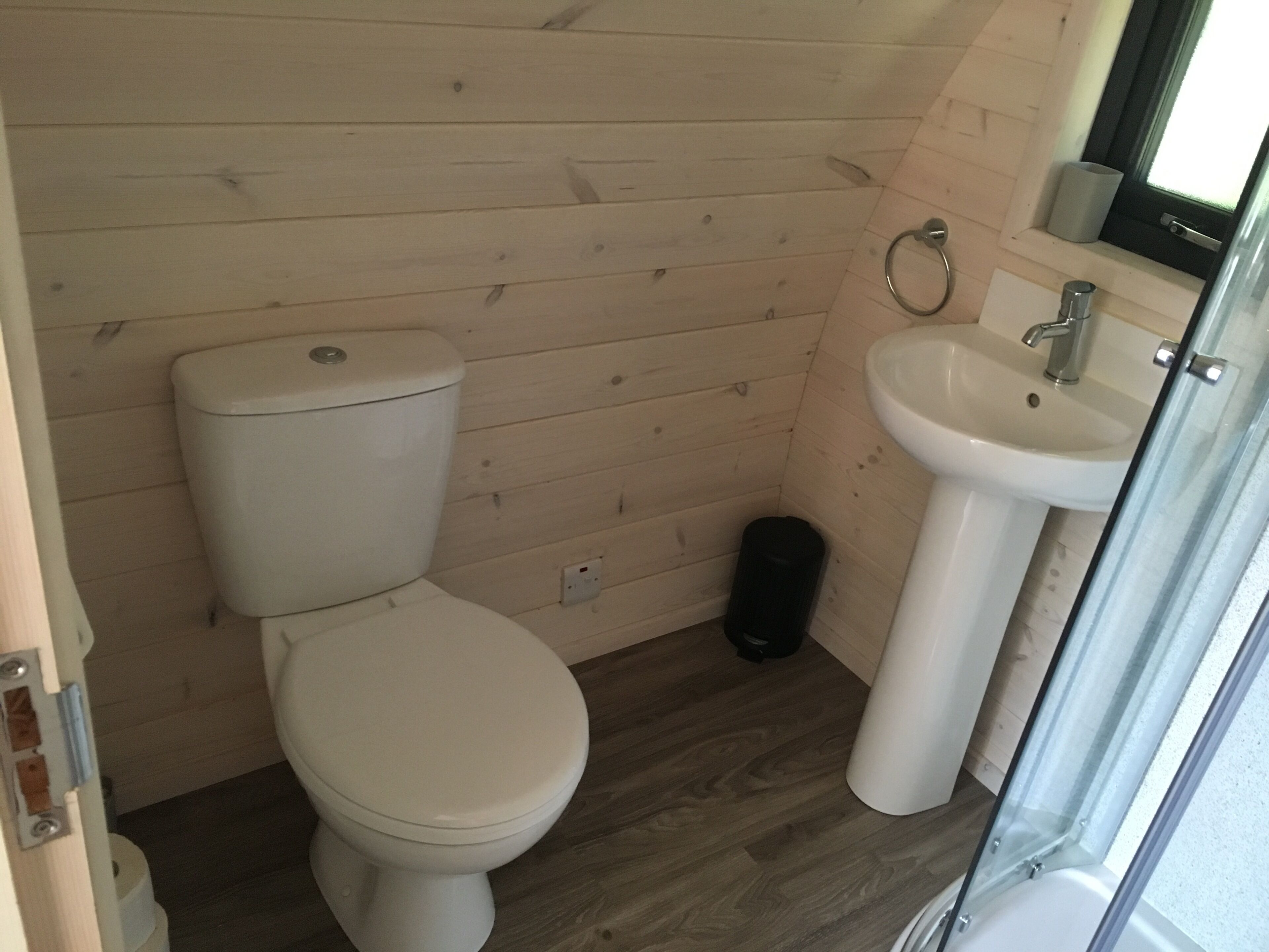 A compact bathroom with a toilet, sink, and a small trash bin.