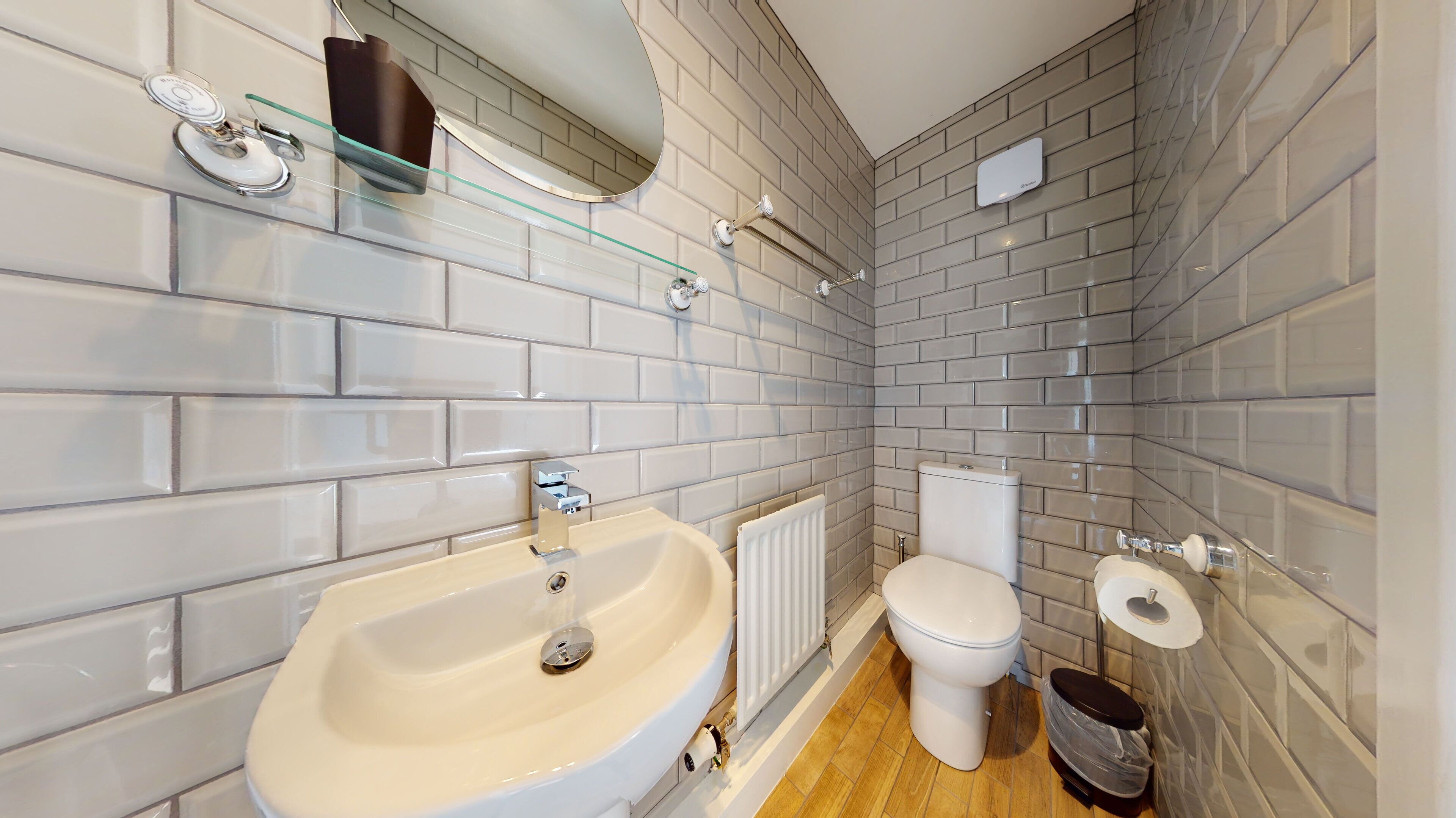 Une salle de bain moderne avec un grand lavabo, des toilettes et une étagère en verre agrémentée d’un miroir.