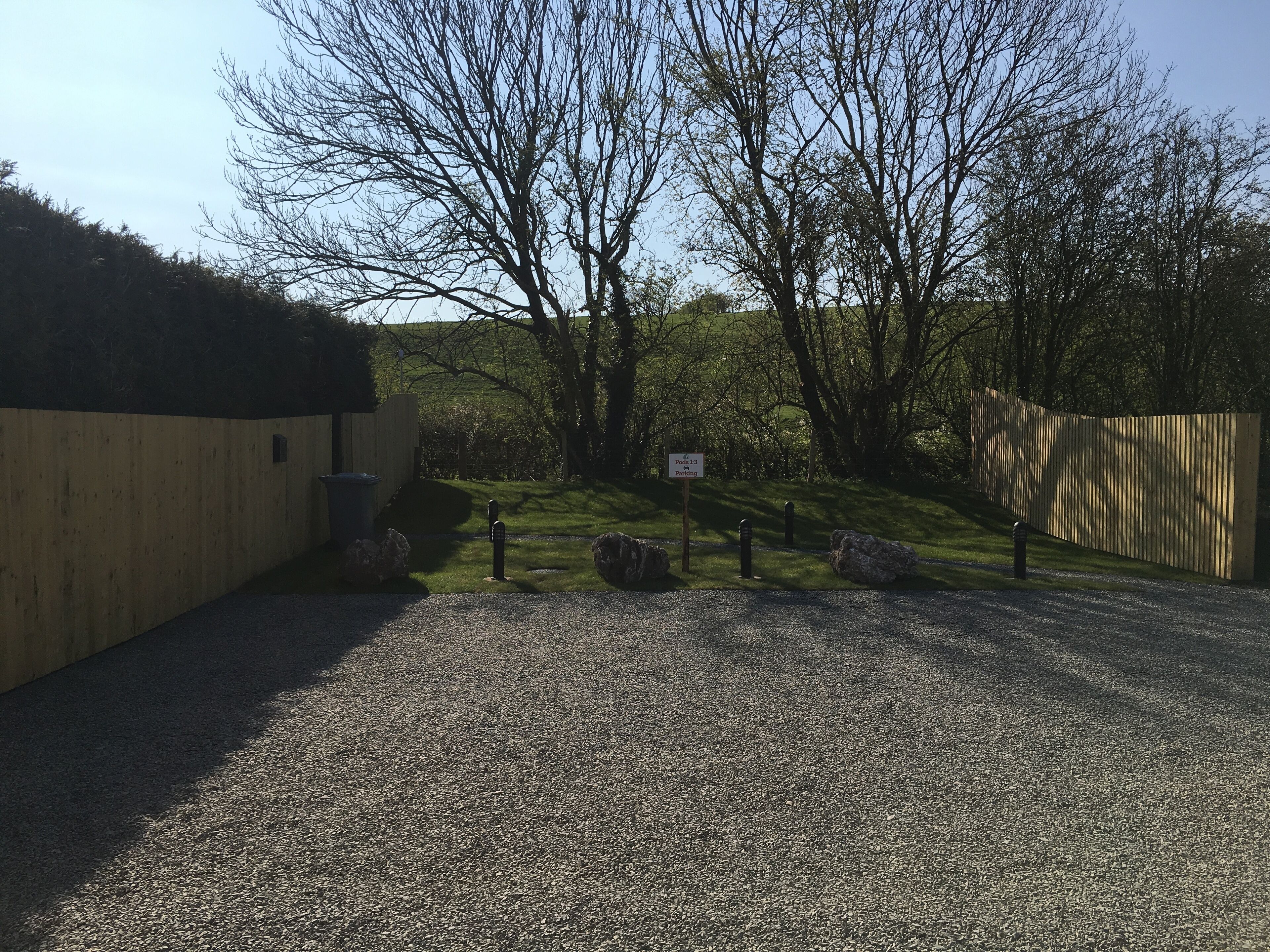 A gravel driveway leading to a wooden gate with a sign indicating parking.