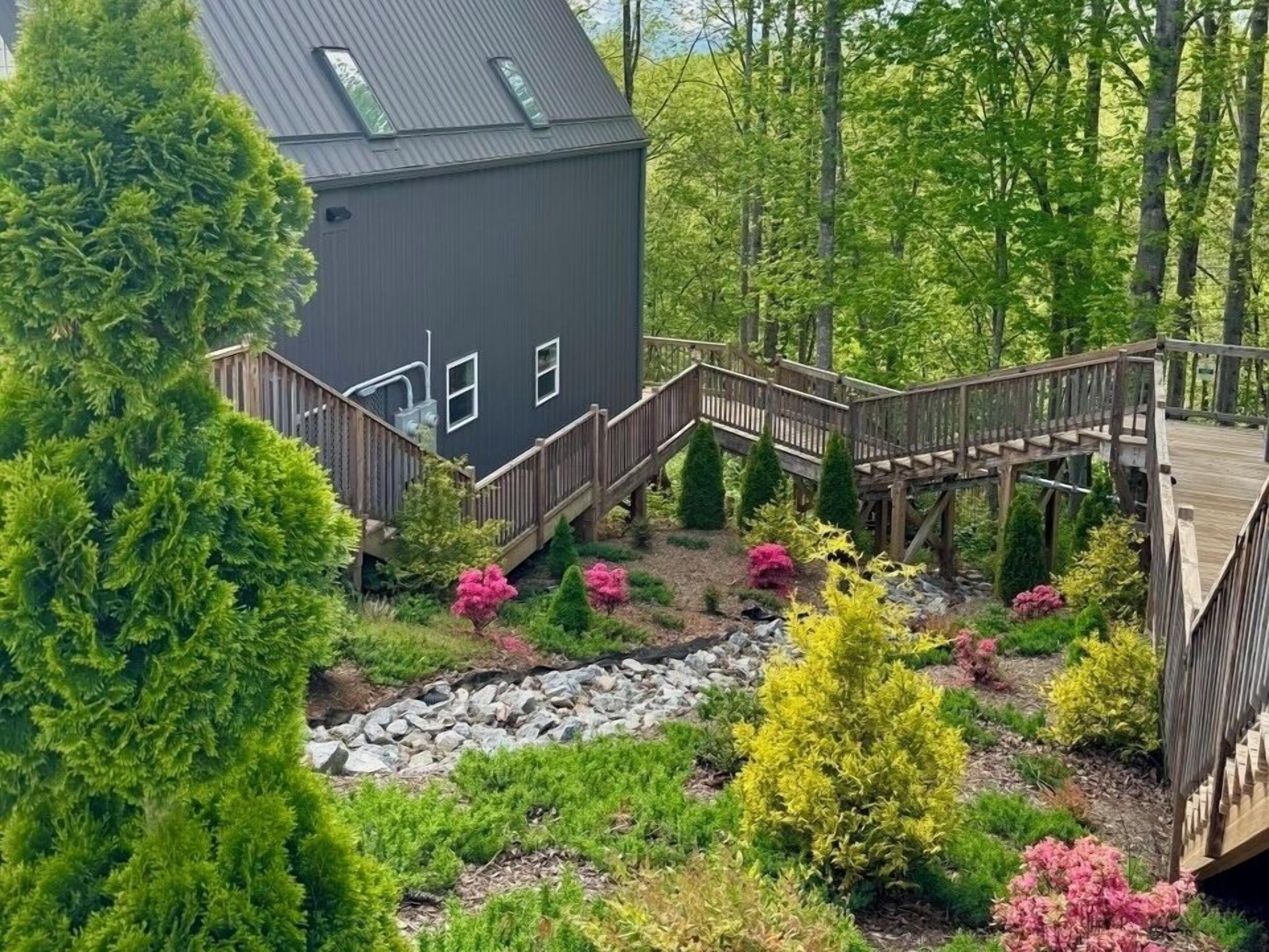 A house with a wooden deck and a stone pathway leading to a wooden staircase.