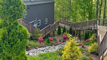 A house with a wooden deck and a stone pathway leading to a wooden staircase.