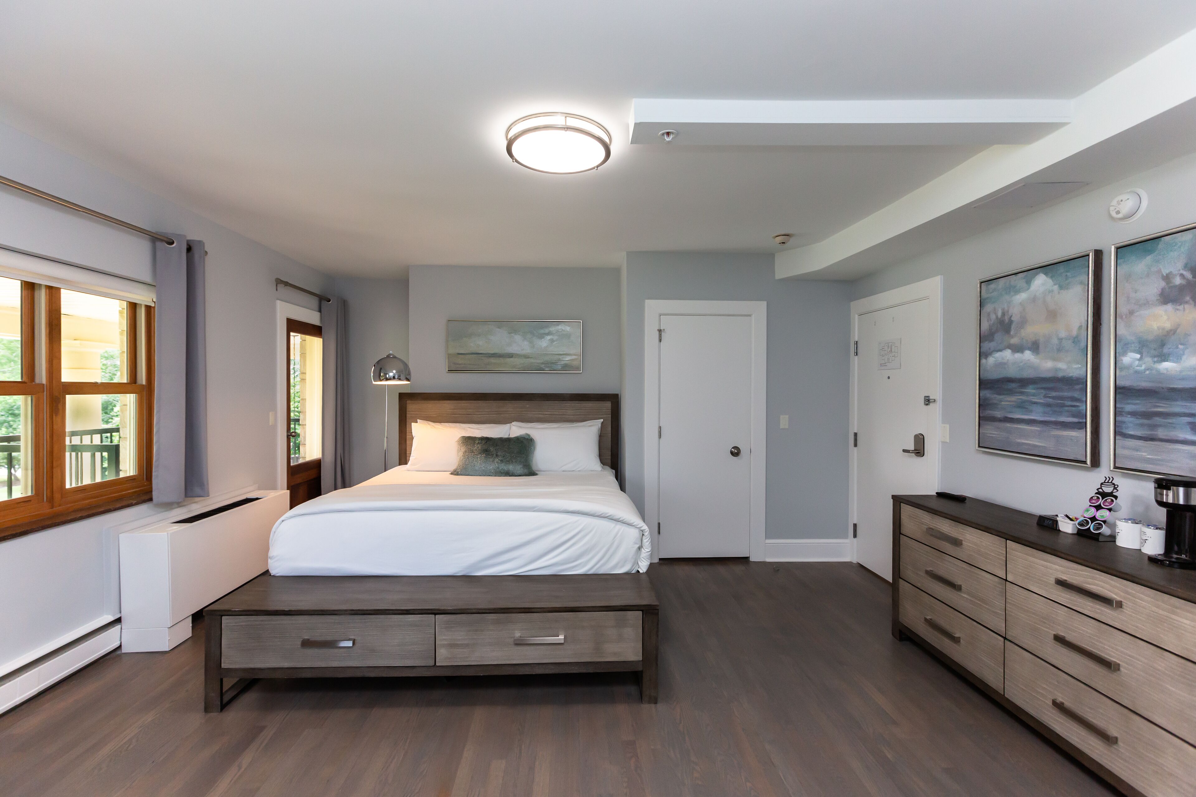 A bedroom with a bed, a dresser, a radiator, and a window.