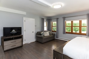 A modern hotel room with a large bed, a sofa, a TV, and a window with curtains. - SKYLARANNA Resort & Spa (Hendersonville)