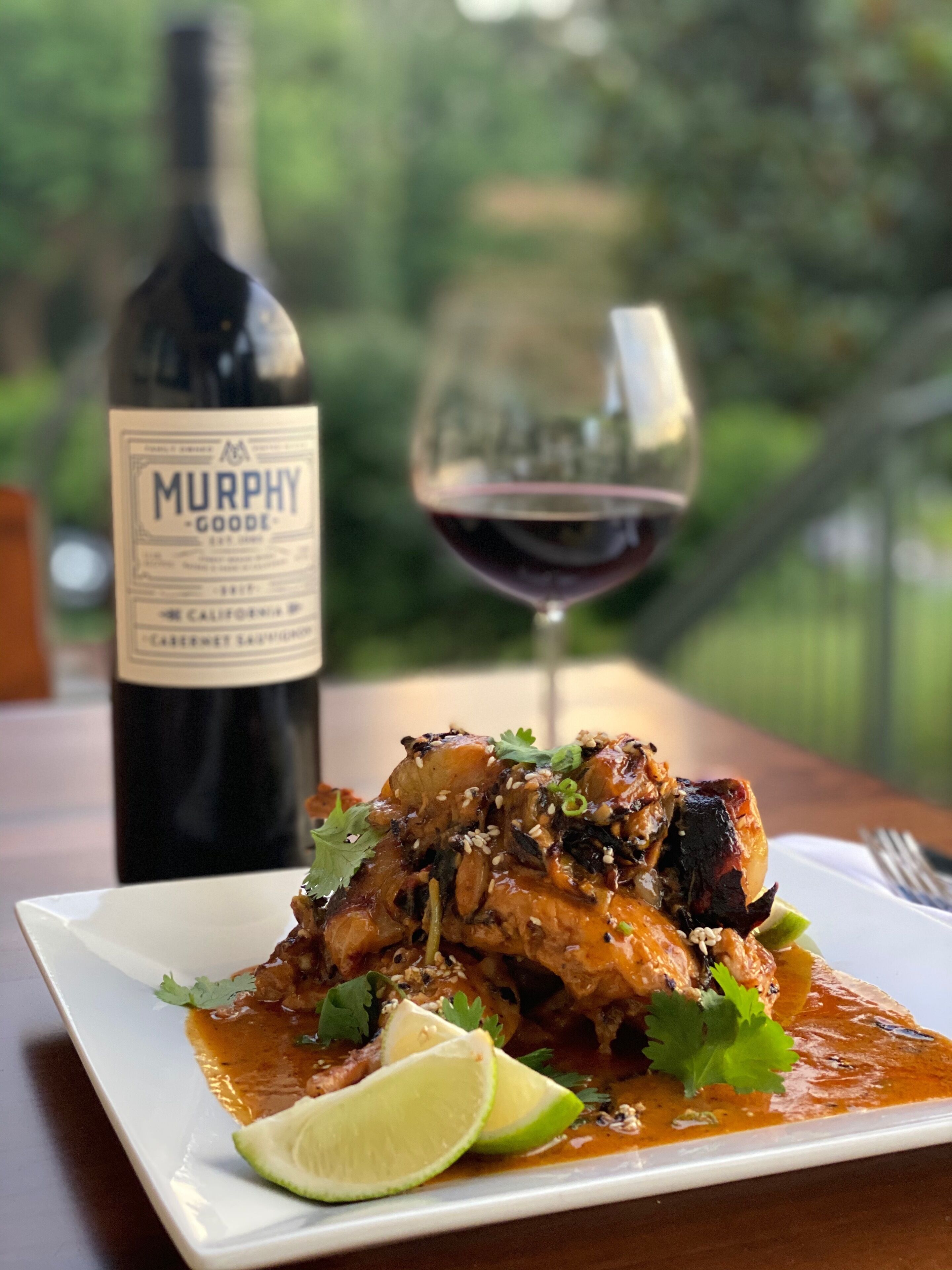 A plate of food with a bottle and a glass of wine on a table.