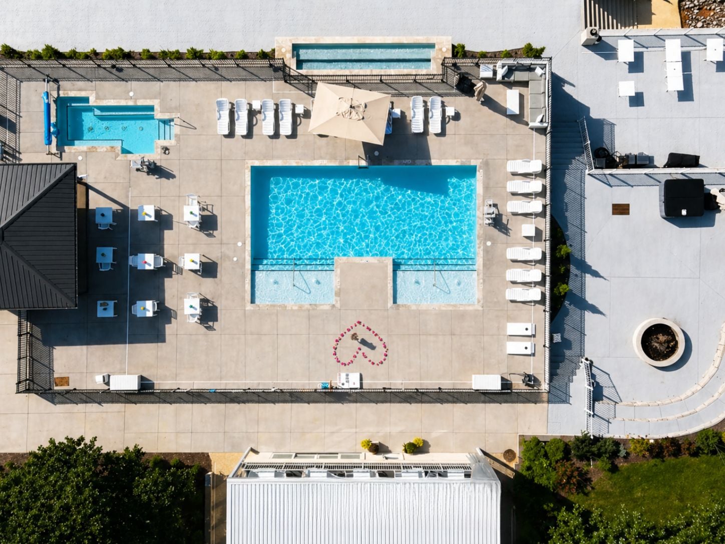 A rooftop pool area with multiple swimming pools, lounge chairs, and a heart-shaped design on the ground.