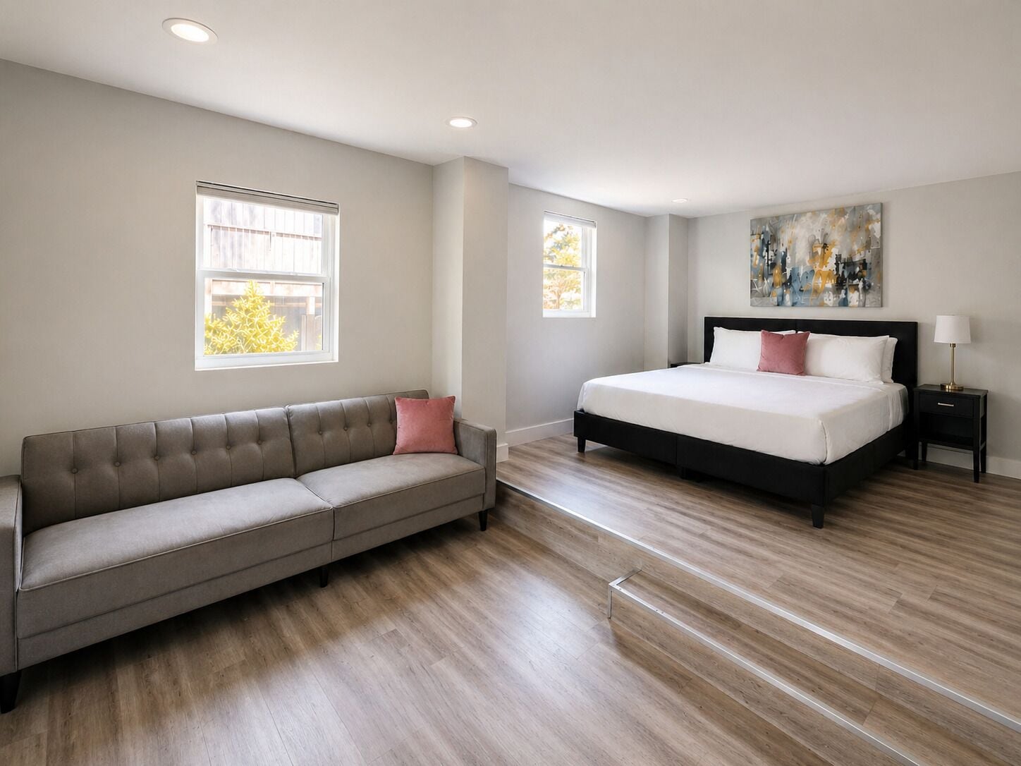 A bedroom with a bed, a sofa, a nightstand, and a painting on the wall.
