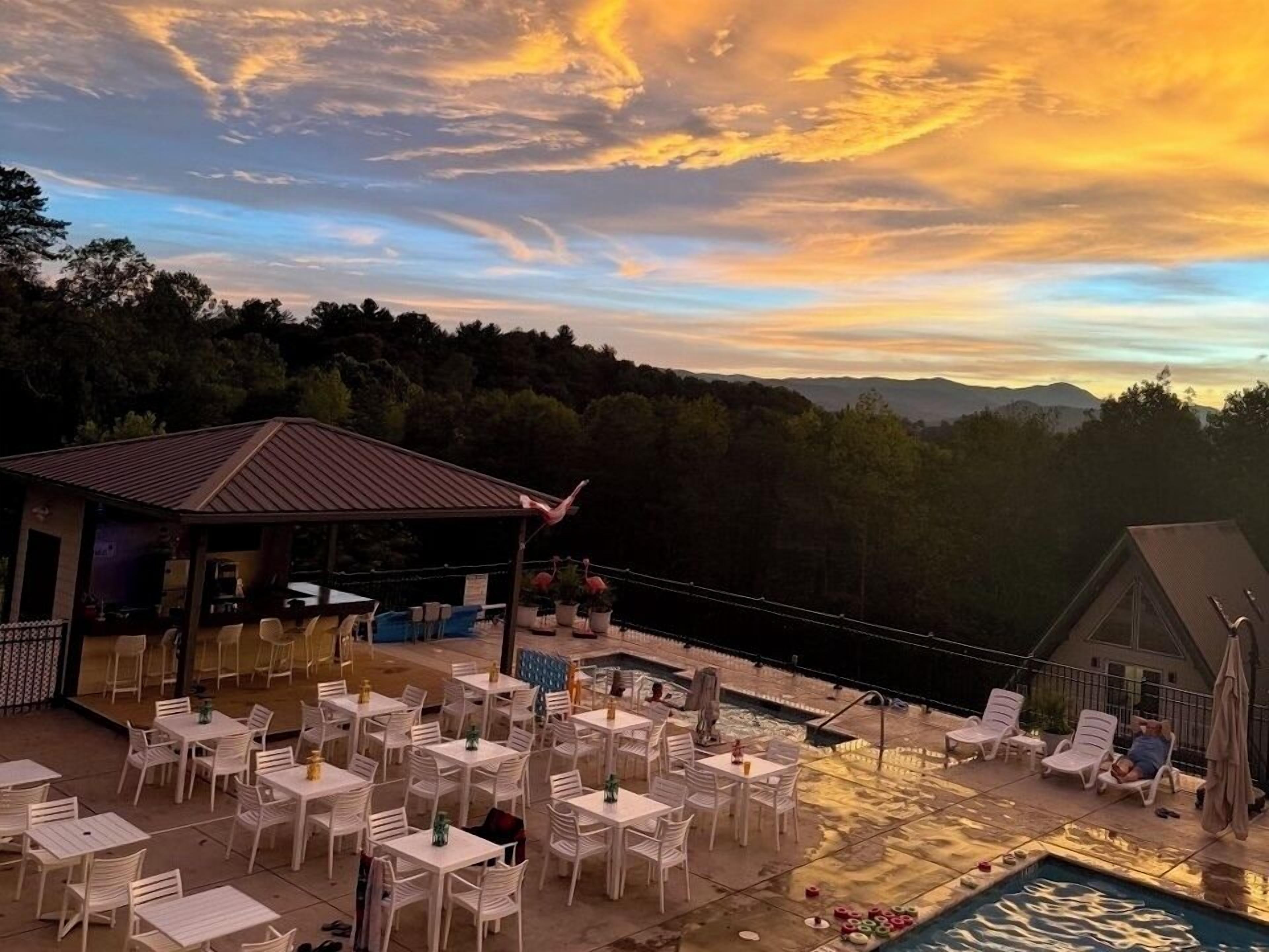 An outdoor dining area with tables and chairs, a pool, and a view of the landscape.