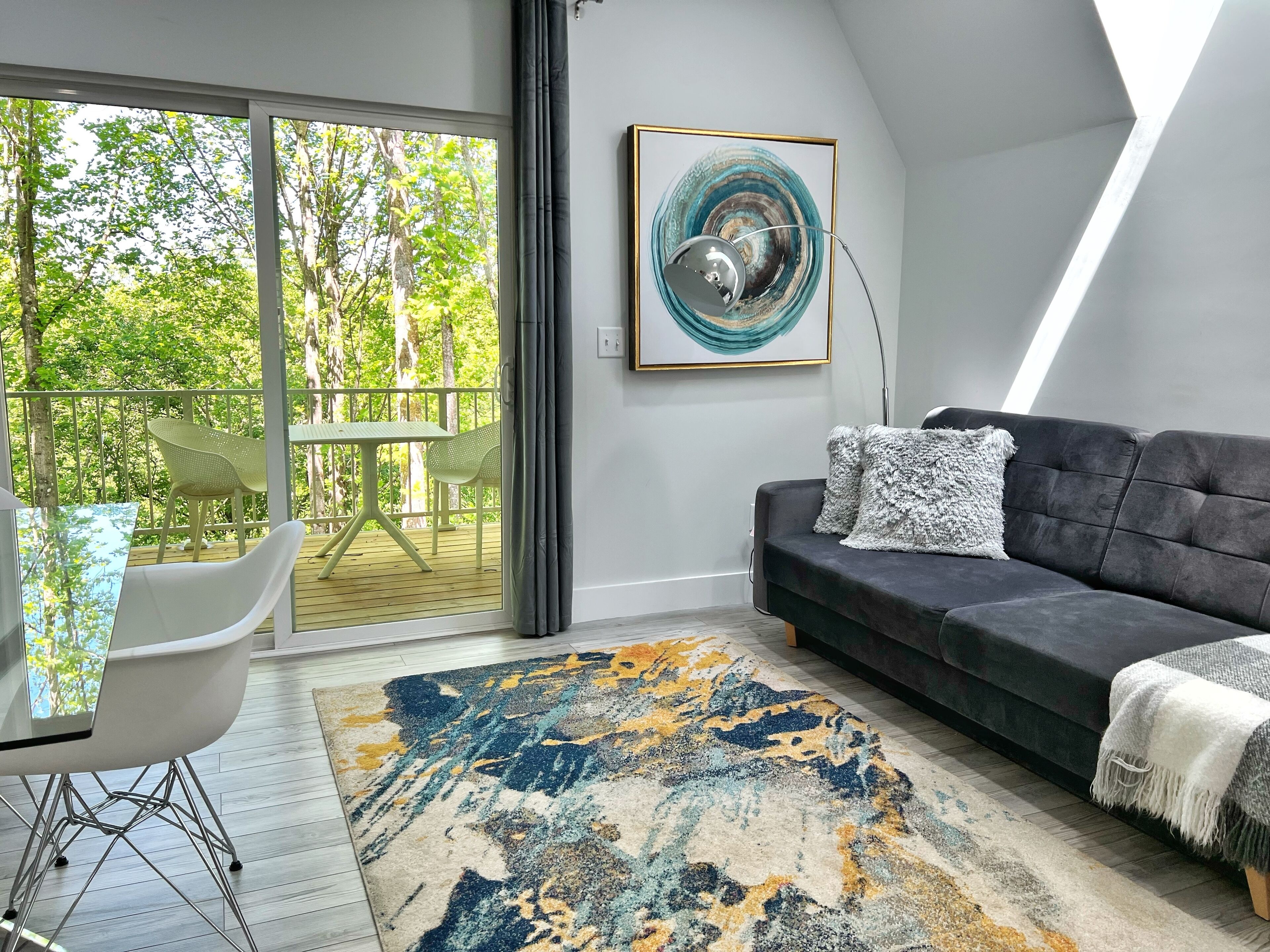 Una sala de estar moderna con un sofá gris, un tapete estampado y un comedor con mesa y sillas.
