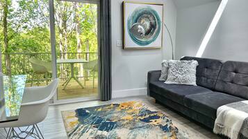 Una sala de estar moderna con un sofá gris, un tapete estampado y un comedor con mesa y sillas.